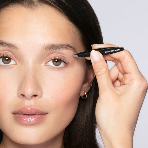 Anwendung einer TWEEZERMAN Mini schrägen Pinzette in schwarz an der linken Augenbraue.