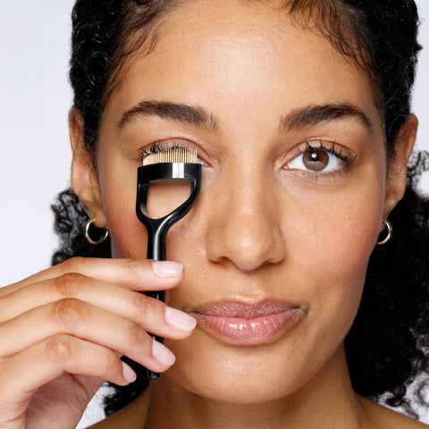 Anwendung eines TWEEZERMAN Wimpernkamms in schwarz am rechten Auge.