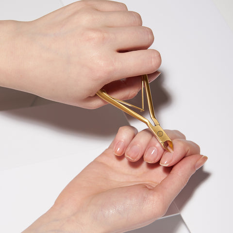 Anwendung einer TWEEZERMAN Ultra Precision Nagelhautzange in gold am rechten Zeigefinger.