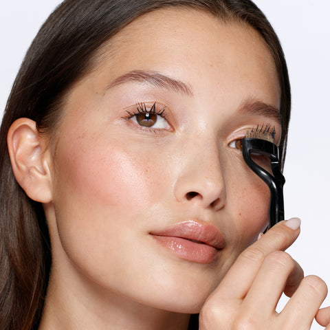 Anwendung eines TWEEZERMAN Wimpernkamms in schwarz am linken Auge.