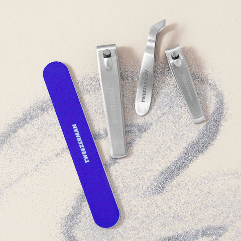 TWEEZERMAN Geschenkset mit verschiedenen Produkten aus rostfreiem Edelstahl speziell für die Nagelpflege, auf weißem Hintergrund mit Glitzer.
