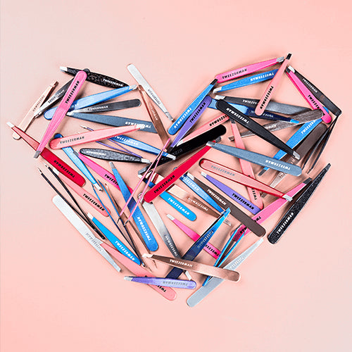 Multicolored Tweezerman tweezers arranged in the shape of a heart on pink background.