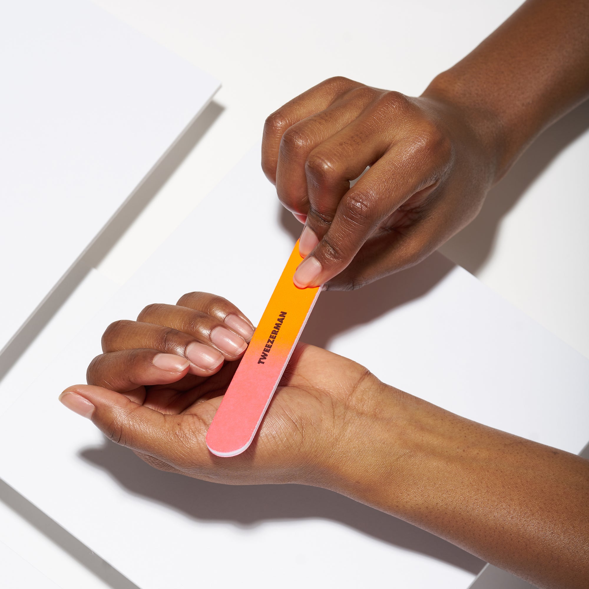 Anwendung einer TWEEZERMAN Nagelfeile in neon an dem linken Ringfinger.