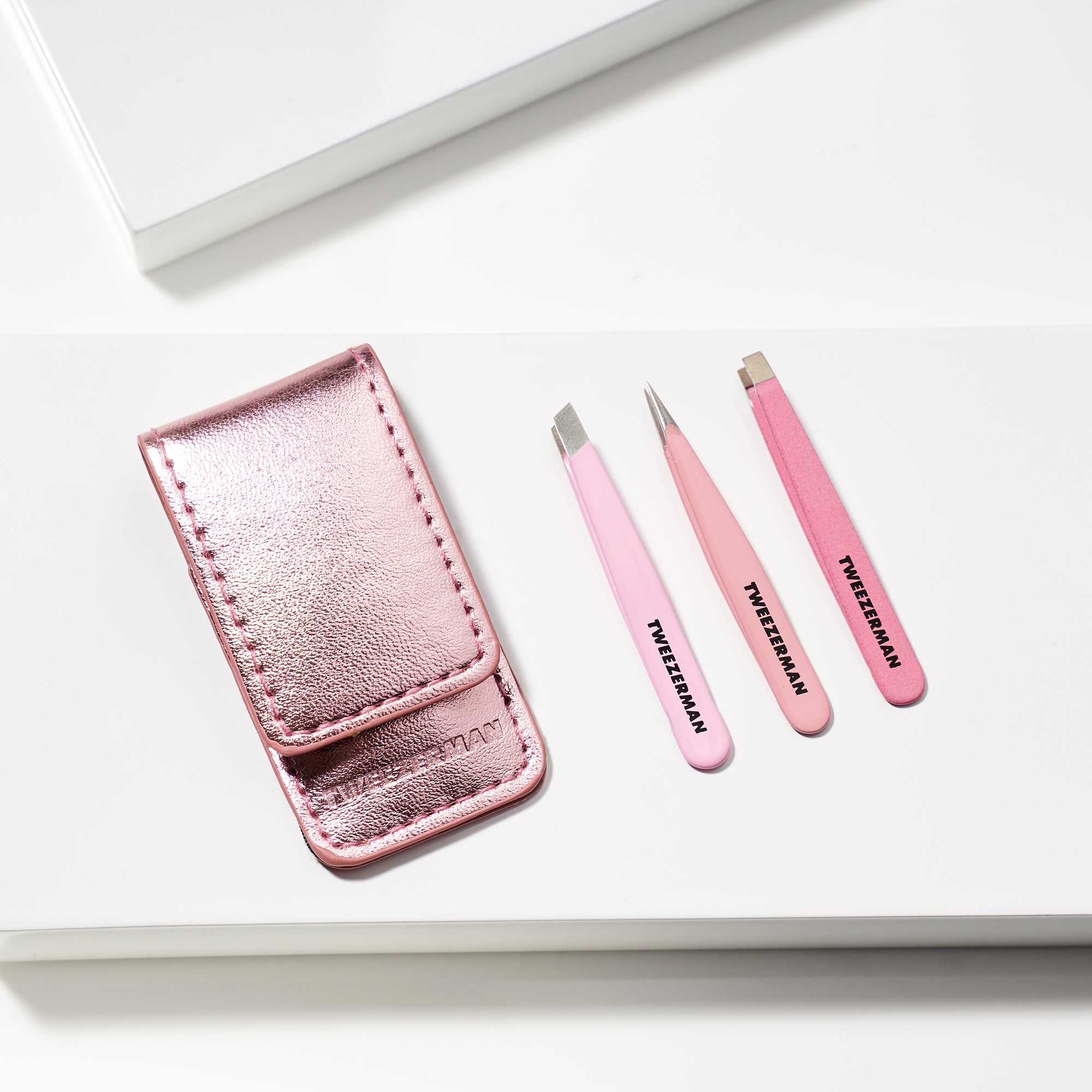 TWEEZERMAN Micro Mini Set mit gerader, spitzer und schräger Pinzette und Etui liegend auf weißen Podesten.