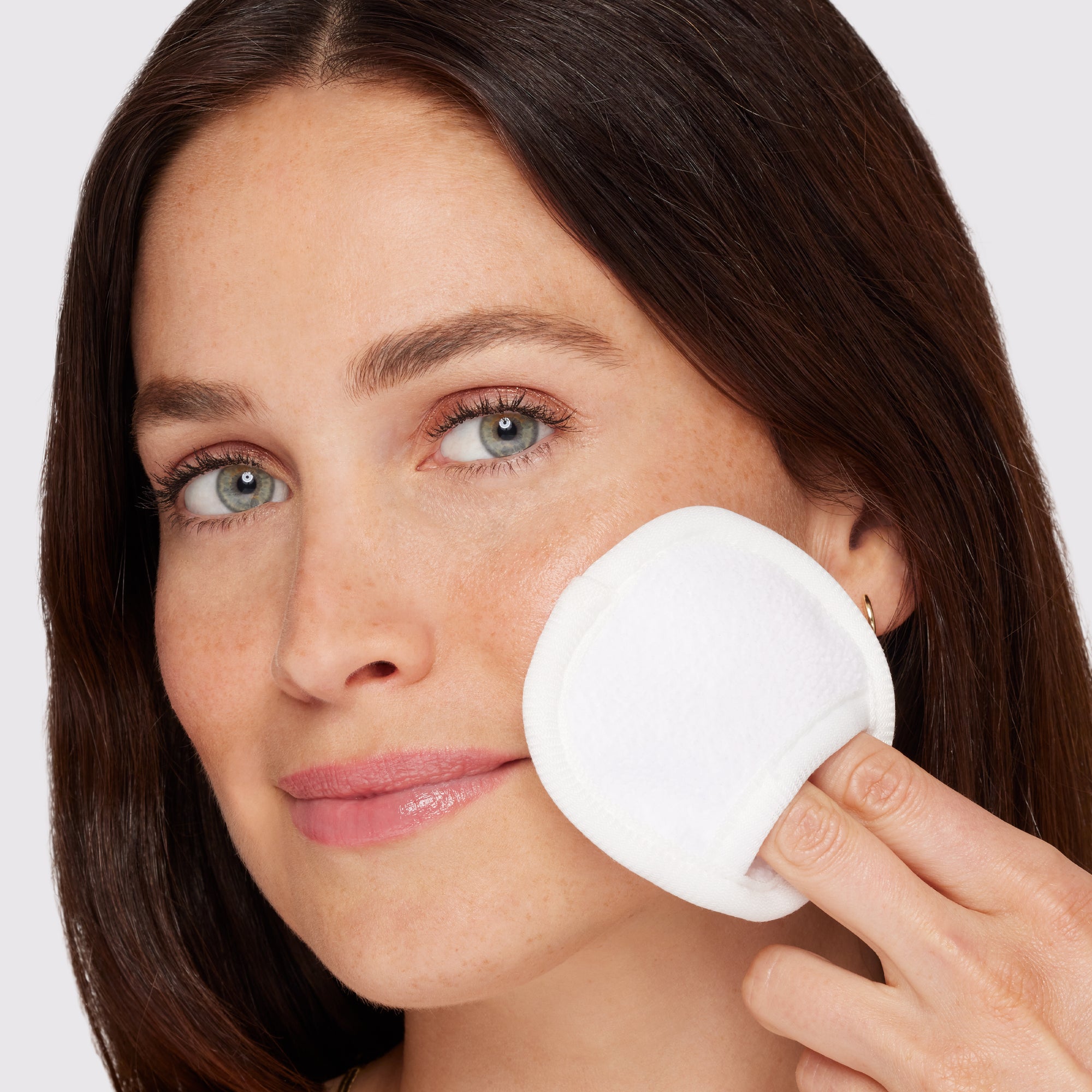 Anwendung eines TWEEZERMAN wiederverwendbaren MakeUp Entferner Pads an der linken Wange.