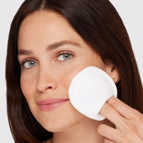 Anwendung eines TWEEZERMAN wiederverwendbaren MakeUp Entferner Pads an der linken Wange.