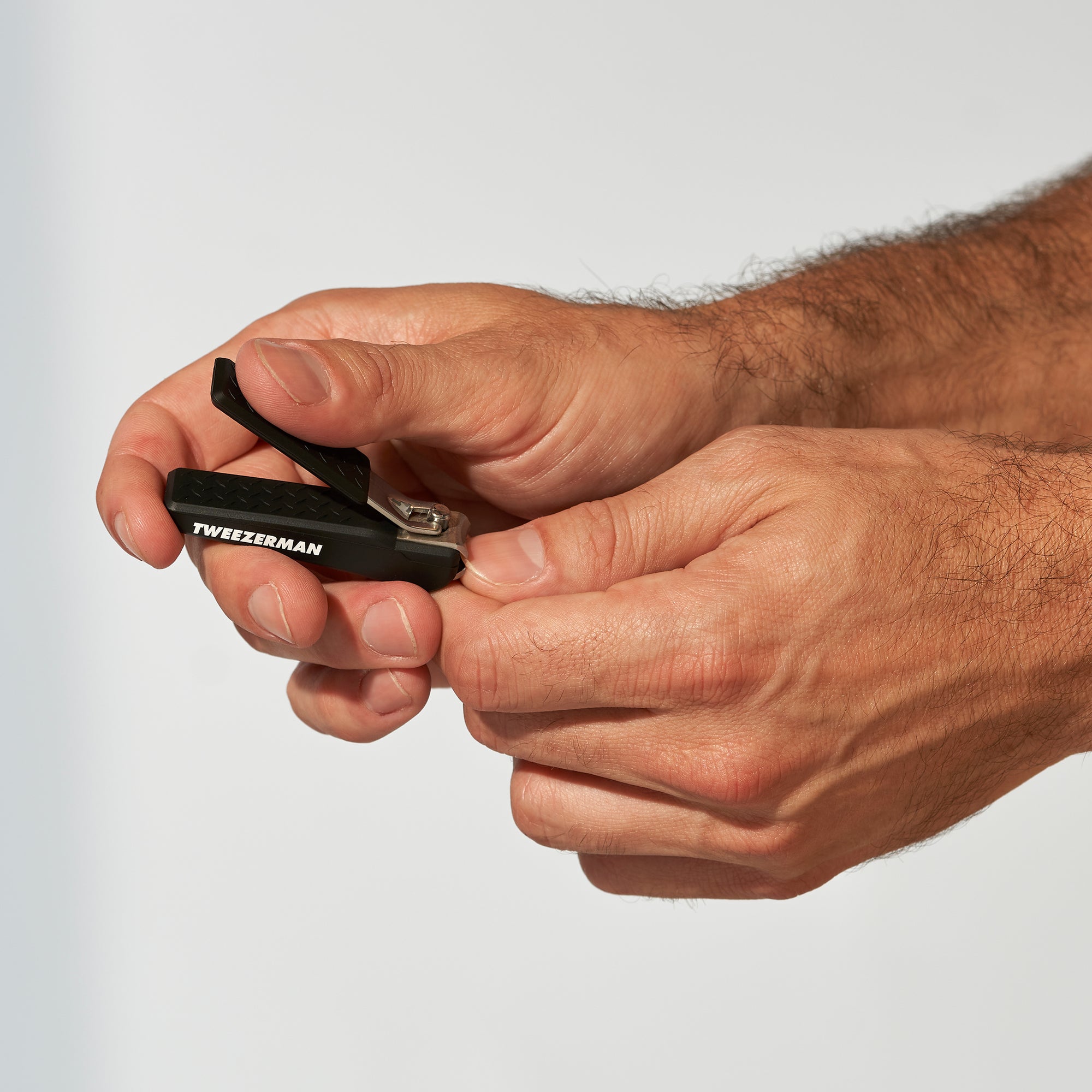 Anwendung eines TWEEZERMAN Nagelknipsers in schwarz an dem rechten Mittelfinger.