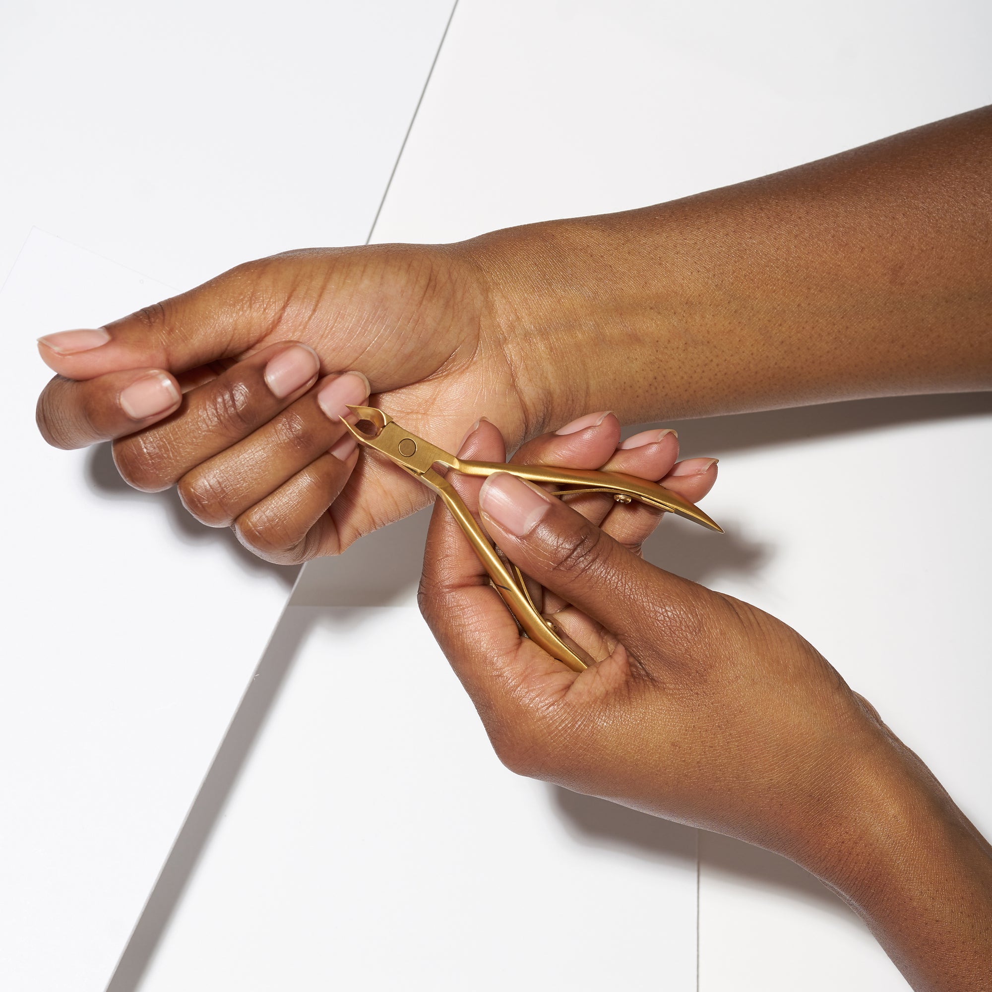 Anwendung einer TWEEZERMAN Ultra Precision Nagelhautzange in gold am rechten Mittelfinger.
