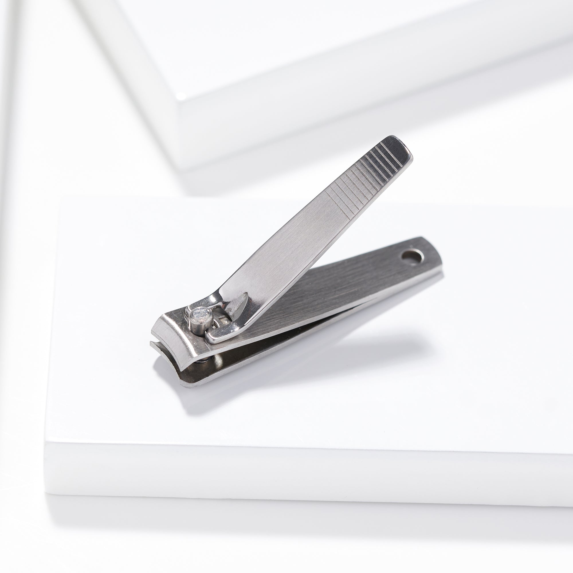 TWEEZERMAN Nagelknipser in silber aus rostfreiem Edelstahl auf weißen Podesten.