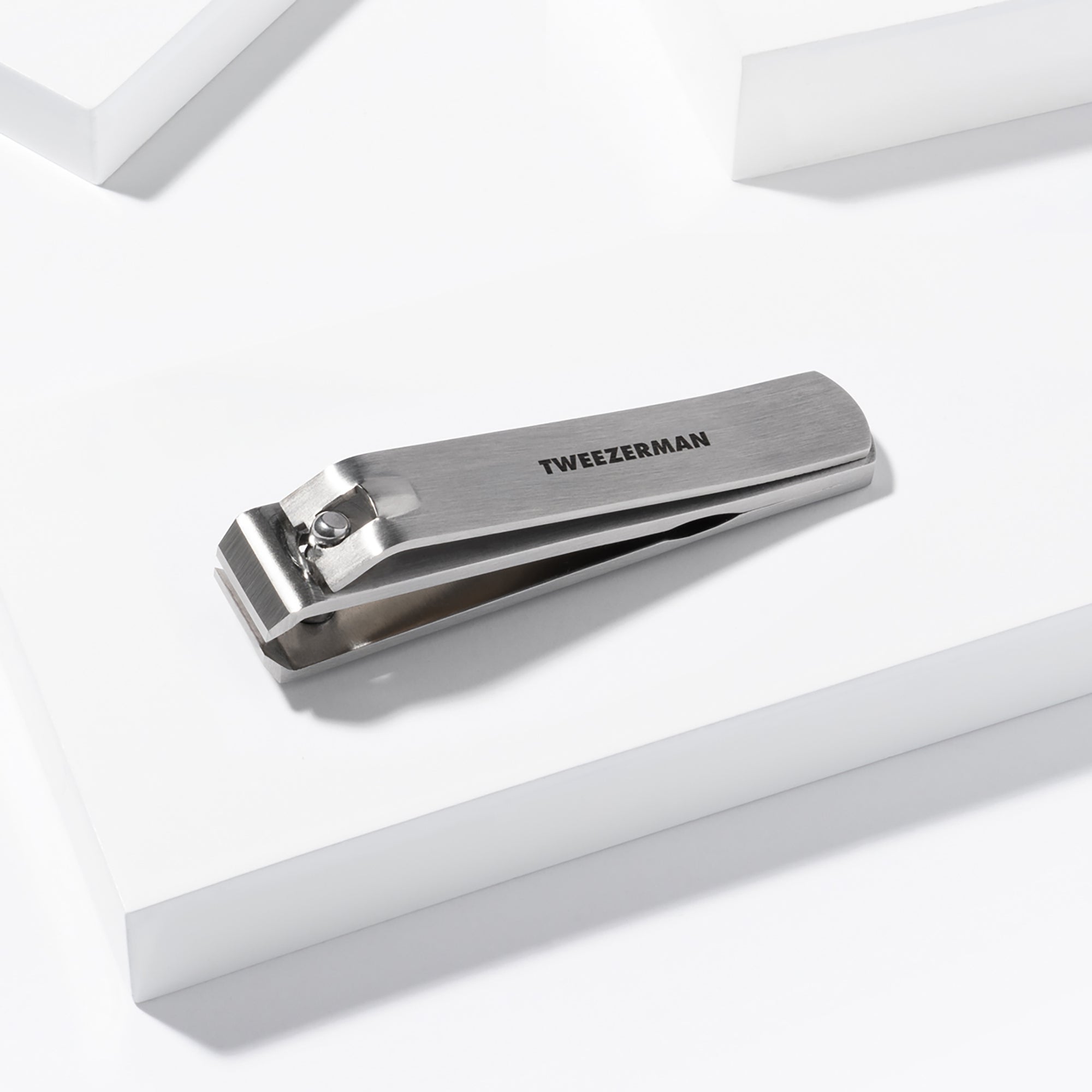 TWEEZERMAN Zehnagelknipser in silber aus rostfreiem Edelstahl auf weißen Podesten.