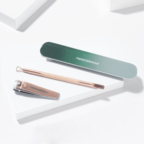 TWEEZERMAN Geschenkset mit diversen Produkten aus rostfreiem Edelstahl speziell für die Nagelpflege auf weißen Podesten.