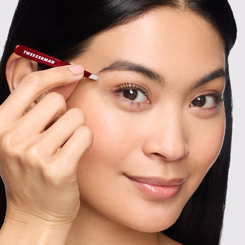 Anwendung einer TWEEZERMAN Schrägen Mini Pinzette in Dunkelrot am rechten Auge mit der rechten Hand.