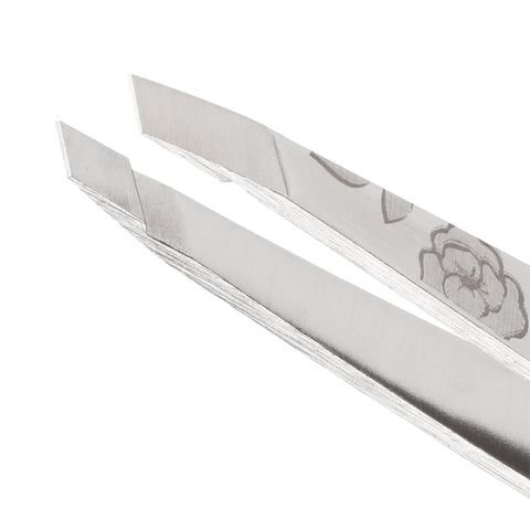 Nahaufnahme der Spitzen einer TWEEZERMAN schrägen Pinzette in silber aus rostfreiem Edelstahl, mit Rosenmuster.