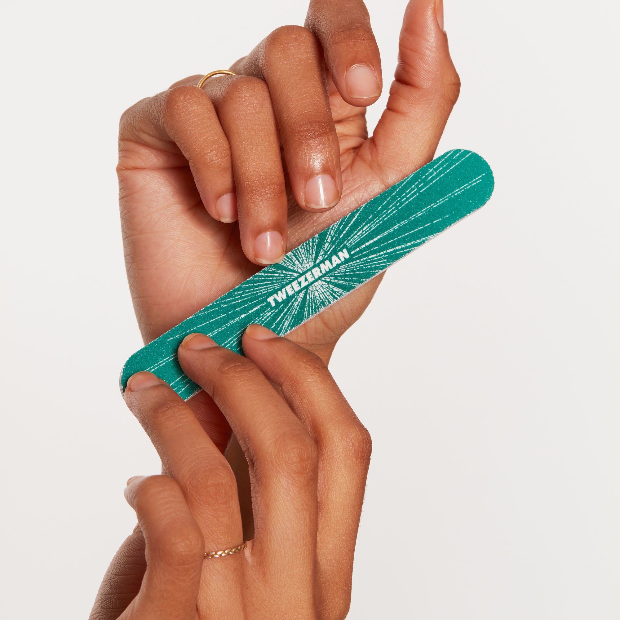 Anwendung einer TWEEZERMAN Nagelfeile in grün an dem linken Ringfinger.